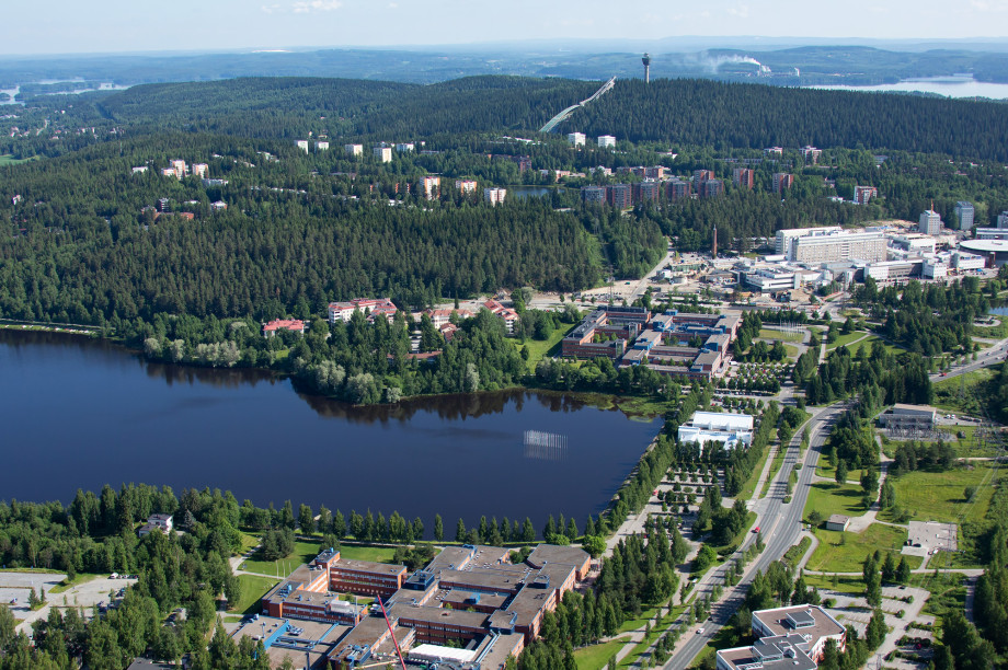 Aerial view of the University of Eastern Finland campus in Kuopio, red-brick buildings beside a lake and forest